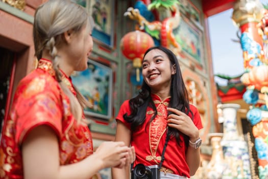 Two women share joy during Chinese New Year worship at a vibrant shrine embracing cultural traditions and community spirit.