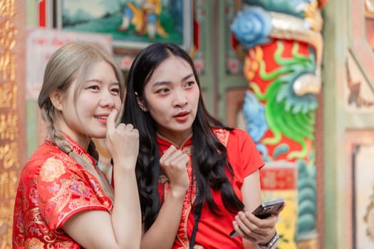 Two friends joyfully celebrate Chinese New Year at a vibrant cultural festival sharing laughter and festive spirit.