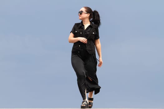 girl in black walking against the sky, emotions and actions