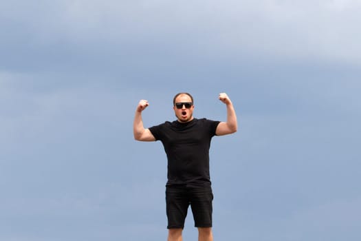 man in black joyfully raised his hands against the sky, emotions and actions