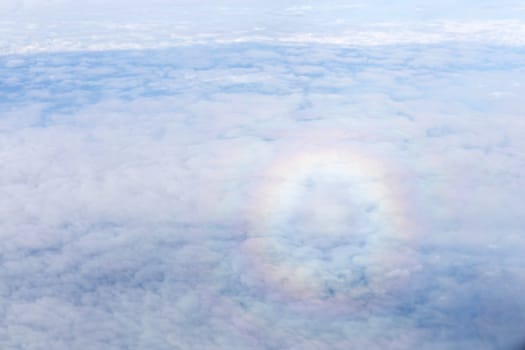 Round rainbow in the cloudy sky. View from the airplane window.