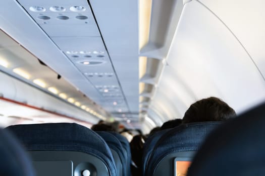 Inside the passenger plane cabin with people. Airplane travel concept.