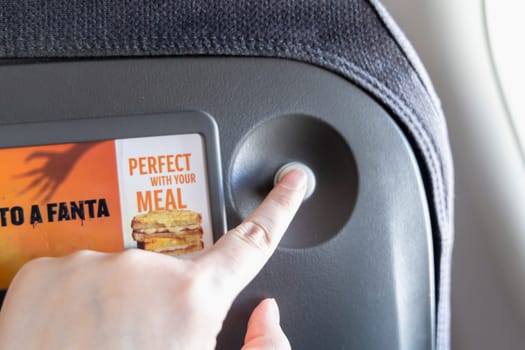 Female hand pressing service button on airplane. Paris, France - January 6, 2025