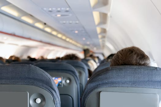 Inside the passenger plane cabin with people. Airplane travel concept.