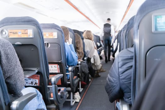 Inside the passenger plane cabin with people. Airplane travel concept. Paris, France - December 6, 2025
