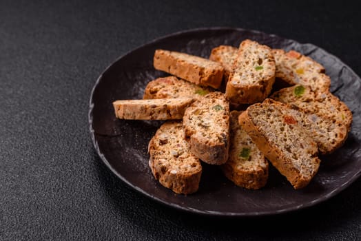 Freshly baked Italian cantuccini cookies with nuts and candied fruits on dark concrete background