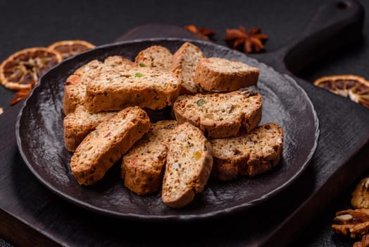 Freshly baked Italian cantuccini cookies with nuts and candied fruits on dark concrete background