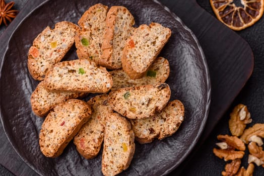 Freshly baked Italian cantuccini cookies with nuts and candied fruits on dark concrete background