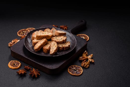 Freshly baked Italian cantuccini cookies with nuts and candied fruits on dark concrete background
