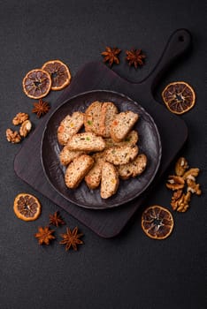 Freshly baked Italian cantuccini cookies with nuts and candied fruits on dark concrete background