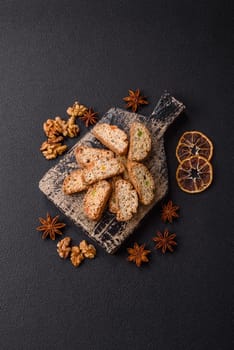 Freshly baked Italian cantuccini cookies with nuts and candied fruits on dark concrete background