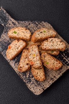 Freshly baked Italian cantuccini cookies with nuts and candied fruits on dark concrete background