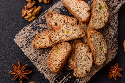 Freshly baked Italian cantuccini cookies with nuts and candied fruits on dark concrete background