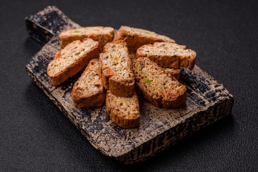 Freshly baked Italian cantuccini cookies with nuts and candied fruits on dark concrete background