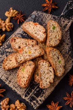 Freshly baked Italian cantuccini cookies with nuts and candied fruits on dark concrete background