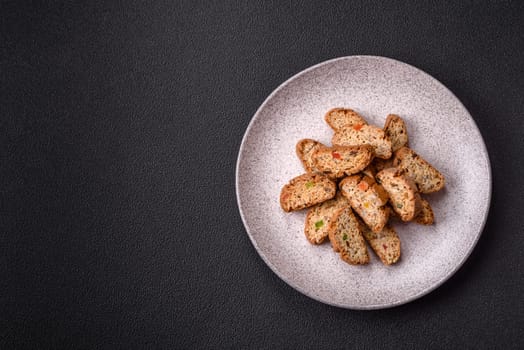 Freshly baked Italian cantuccini cookies with nuts and candied fruits on dark concrete background