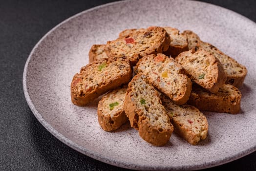 Freshly baked Italian cantuccini cookies with nuts and candied fruits on dark concrete background