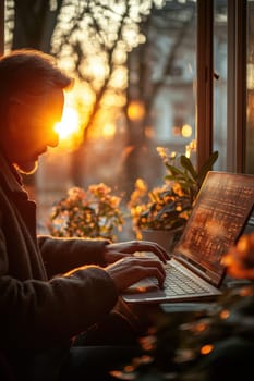 Close-up of a man's hand typing on a keyboard in the background of the sunset outside the window. Writing a letter on a laptop keyboard.