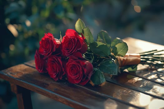 A beautifully arranged bouquet of red roses tied with natural greenery rests elegantly on a wooden surface, exuding romance and charm, perfect for any special occasion.