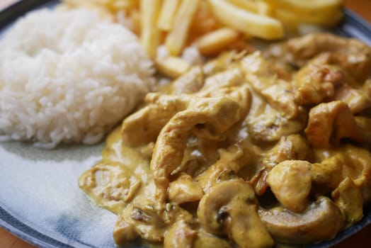Savor a delicious chicken curry served with fluffy rice and crispy fries for a satisfying meal