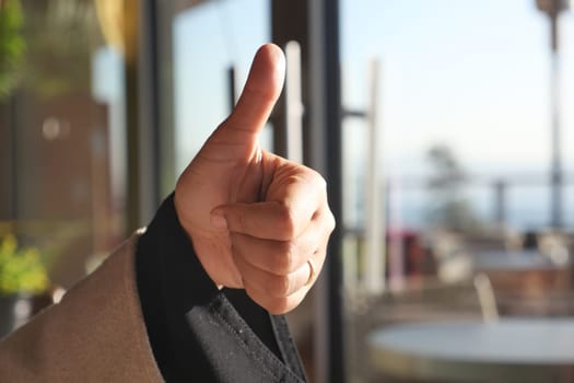 A hand confidently giving a thumbs up in a bright indoor space, highlighting positivity