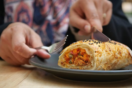 A closeup image shows someone skillfully cutting a wrap on a plate for easier eating