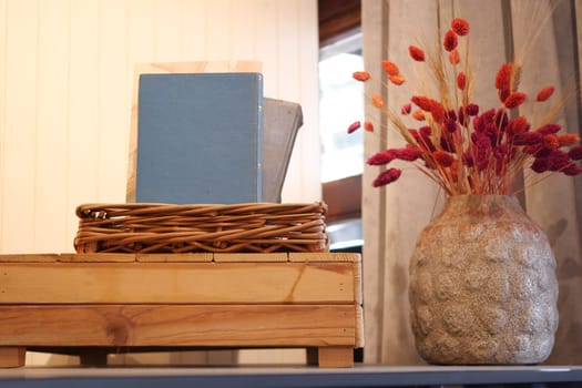A wooden bookshelf with books, vase of orange flowers in front of a wooden panel wall