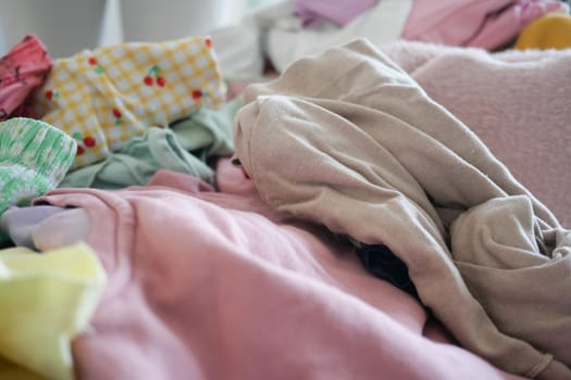 A vibrant and colorful assortment of casual garments is scattered messily across a bed