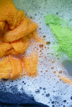 Vibrant and colorful sponges soaking in a bubbly, frothy cleaning solution full of foam