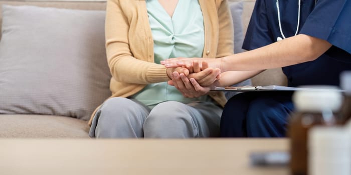 A caregiver consults a doctor and nurse while checking the symptoms of an elderly patient in a cozy home setting.