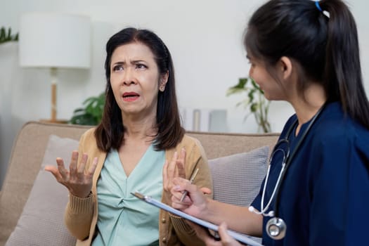 A nurse discusses symptoms with an elderly patient highlighting the importance of caregiver support in healthcare.
