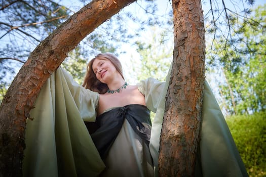 Beautiful dryad or fairy near trees. Pagan spirit of forest. Environmental friendliness, caring for nature. Adult mature woman 40-60 in Photo shoot
