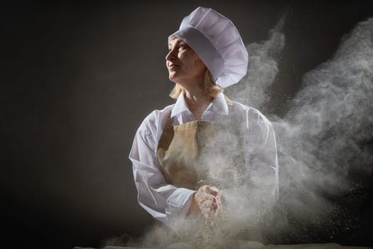 A lively elderly woman is joyfully preparing dough from flour in a fun kitchen setting while posing for a lighthearted photo.