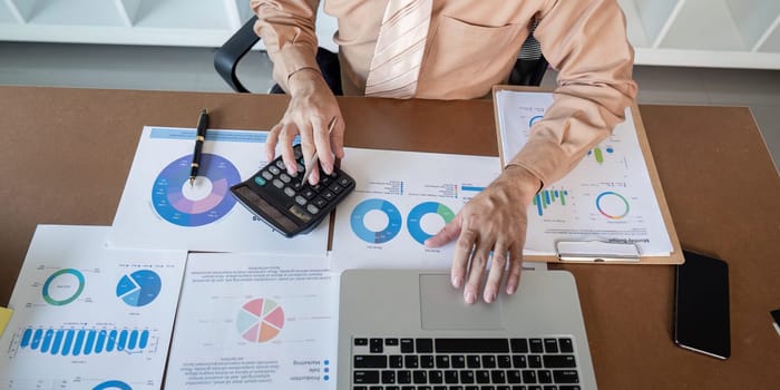 A focused professional reviews charts and data on a work desk.
