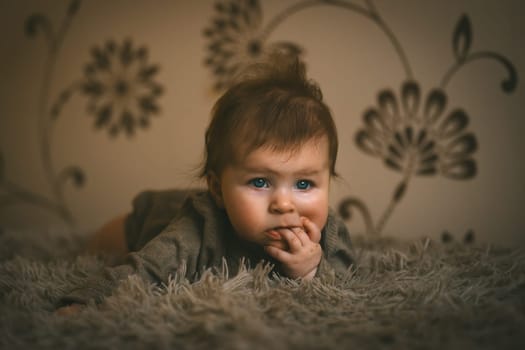 Cute baby girl in brown clothes close up crawling on bed. Adorable kid portrait. 5 month old child. High quality photo