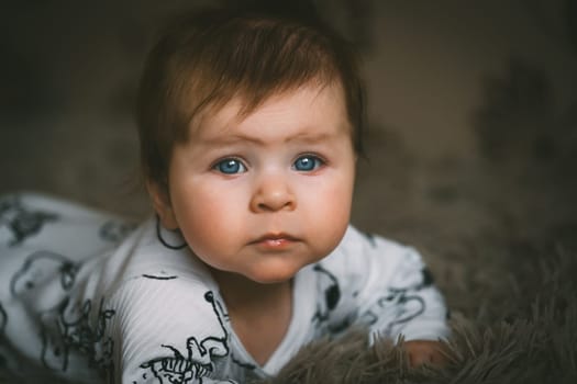 Cute baby girl close up lying on bed. Adorable kid portrait. 5 month old child. Childhood and baby concept. High quality photo