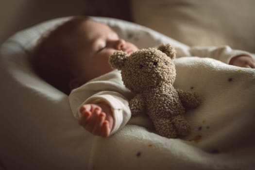 Sleeping newborn baby lying with a soft teddy bear under the blanket in warm, cozy sunlight. Childhood and parenting concept. High quality photo