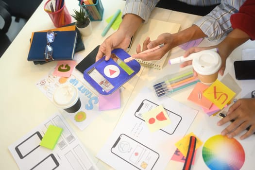 UX designers analyzing colorful charts and app interface wireframes during brainstorming.