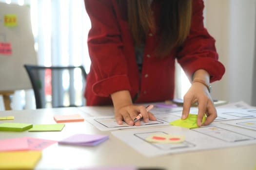 Team of creatives collaborating on a UX UI project at workspace filled with flowcharts and digital prototypes.