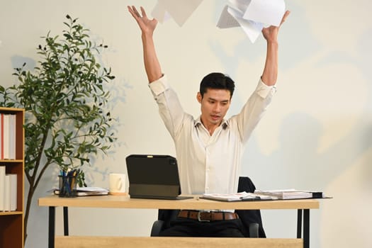 Frustrated businessman throwing documents in anger. Stress at work concept.