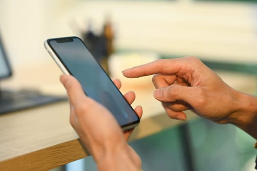 Close up businessman in black suit typing message on his mobile phone.