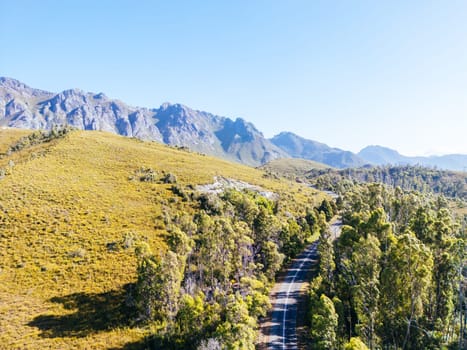 An aerial view of Gordon River Rd at the Sentinel range of mountains near Bitumen Bones Sculpture on a hot summer's afternoon in Southwest National Park, Tasmania, Australia