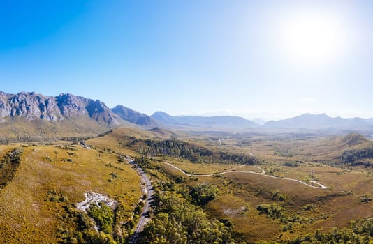 An aerial view of Gordon River Rd at the Sentinel range of mountains near Bitumen Bones Sculpture on a hot summer's afternoon in Southwest National Park, Tasmania, Australia