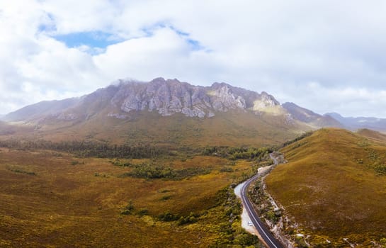 An aerial view of Gordon River Rd at the Sentinel range of mountains near Bitumen Bones Sculpture on a hot summer's afternoon in Southwest National Park, Tasmania, Australia