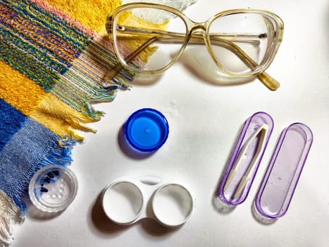 Prescription glasses and contact lenses are carefully arranged on a vibrant cloth with a lens case and cleaning supplies nearby, ready for use.
