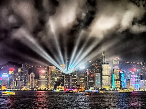 Hong Kong - April 05, 2024: At dusk, the skyline of Hong Kong comes alive with a spectacular light show over Victoria Harbour. Colorful beams illuminate the city, creating a mesmerizing atmosphere.