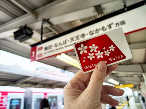 Tokyo, Japan - October 29, 2024: Tourist holds a welcome Suica transport card in a bustling subway station in Japan, ready for easy access to public transit.
