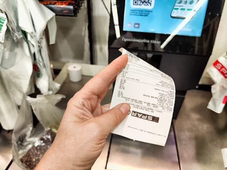 Kazan, Russia - August 27, 2024: Customer holds a receipt at a self-service checkout station in a grocery store located in Kazan, Russia