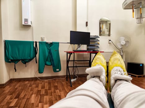 Kirov, Russia - November 28, 2024: Patient prepares for X-ray exam in a hospital room with necessary equipment and safety gear visibly present.
