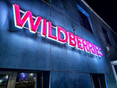 Kirov, Russia - November 19, 2024: Brightly lit logo of an online marketplace shines on the building facade during nighttime, showcasing modern retail identity.